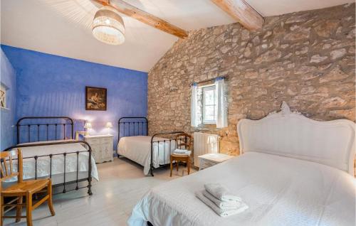 1 dormitorio con 2 camas y pared de piedra en Lovely Home In Lacoste With Kitchen, en Lacoste