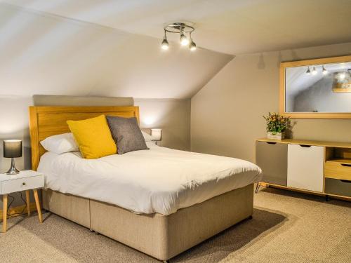 a bedroom with a large bed with a yellow pillow at The Dairy in Crossmichael