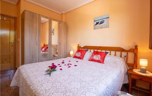 グアルダマル・デル・セグラにあるBeautiful Apartment In Guardamar Del Segura With 2 Bedrooms And Outdoor Swimming Poolの赤い枕と花が飾られたベッドルーム1室が備わります。