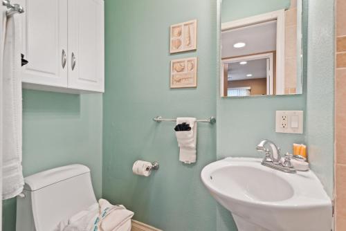 een badkamer met een wastafel, een toilet en een spiegel bij 309A - Ocean and Beach View in Oceanside