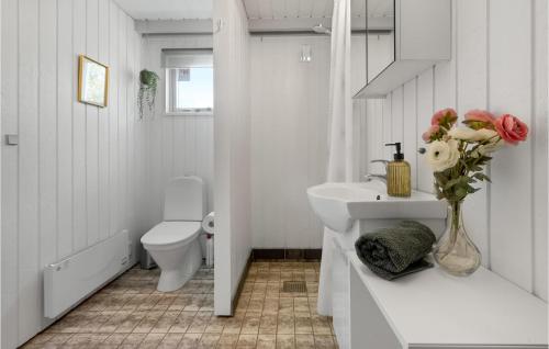 a bathroom with a sink and a toilet and a vase of flowers at 3 Bedroom Gorgeous Home In Toftlund in Vestergård