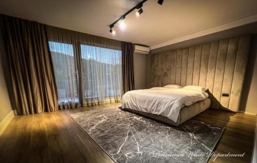 a bedroom with a bed and a large window at Pensiunea White Department in Vlădeşti