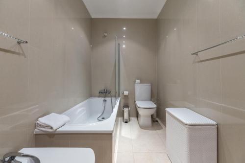 ein weißes Bad mit einer Badewanne und einem WC in der Unterkunft Akivillas Albufeira Dawnstar in Olhos de Água