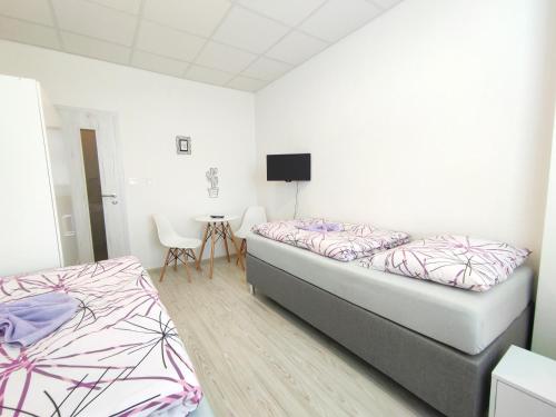 a bedroom with two beds and a table with chairs at Hotel Slobi in Štúrovo