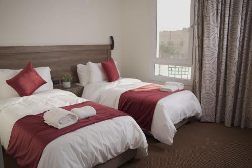 two beds in a hotel room with towels on them at Petra Passion Inn in Taiyiba