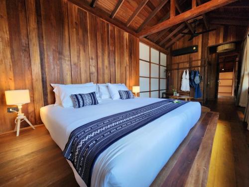 uma grande cama branca num quarto com paredes de madeira em Athita The Hidden Court Chiang Saen Boutique Hotel SHA Plus CERTIFIED em Chiang Rai