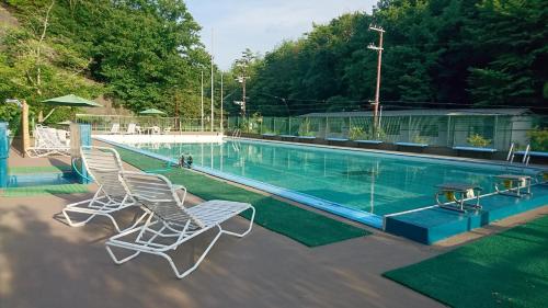 a swimming pool with two white chairs next to it at Ryokan Sumiya Kihoan in Kameoka