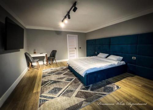a bedroom with a bed and a desk with chairs at Pensiunea White Department in Vlădeşti