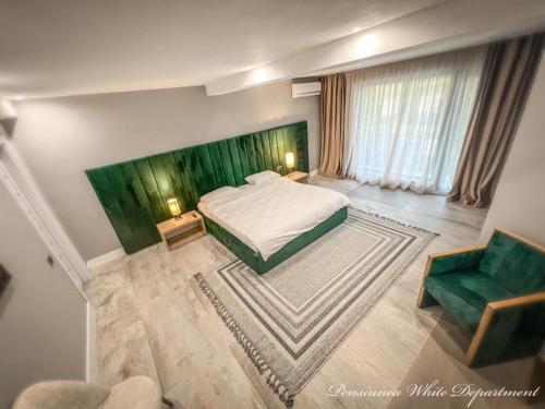 a bedroom with a bed and a green headboard at Pensiunea White Department in Vlădeşti