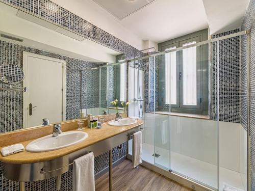 Un baño con dos lavabos y una ducha. en H10 Raco del Pi, en Barcelona