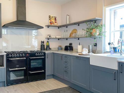 a kitchen with a black stove and a sink at Corner Cottage in Alburgh