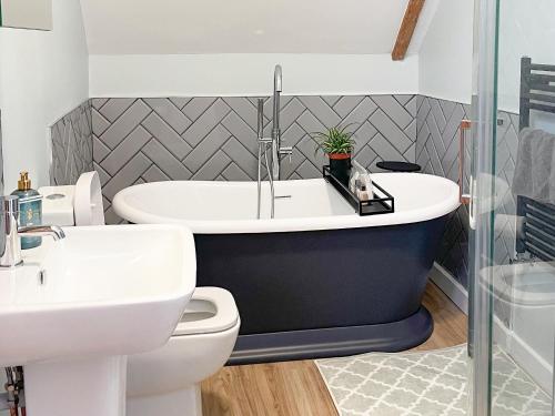 a bathroom with a tub and a toilet and a sink at Corner Cottage in Alburgh