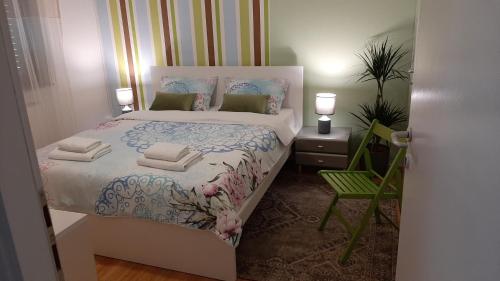 een kleine slaapkamer met een bed en een groene stoel bij Apartman Mi-Bel in Zagreb
