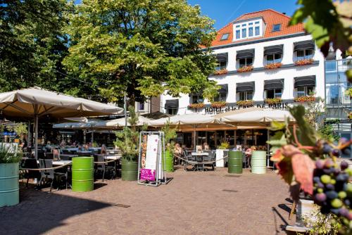 une cour avec des tables, des chaises et des parasols dans l'établissement Hotel et le Cafe de Paris, à Apeldoorn