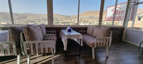 a table and chairs in a room with a view at Beit Alshabaan Inn in Wadi Musa