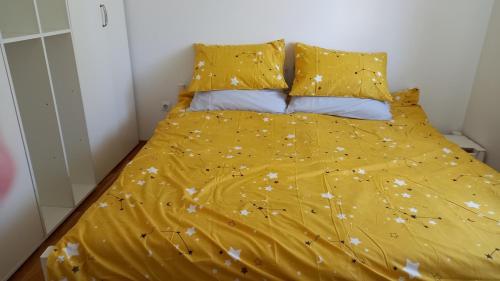 a bed with a yellow comforter and pillows at Domaćinska kuća in Arandelovac