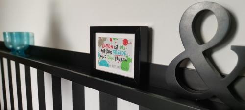 a framed picture sitting on a rail next to a glass at Villa Kunterbunt, Gemütlichkeit am Waldesrand in Drangstedt