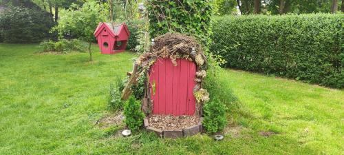 a garden with a red door and a bird house at Villa Kunterbunt, Gemütlichkeit am Waldesrand in Drangstedt