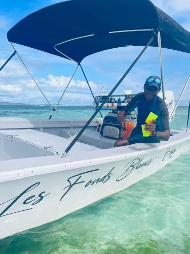 a man sitting on a boat in the water at VILLA CAPACITE 6 PERSONNES PROCHE PLAGES DU Sud in Rivière-Pilote
