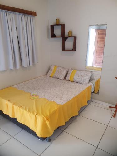 um quarto com uma cama com um cobertor amarelo em Pousada Monte Carlos em Galinhos