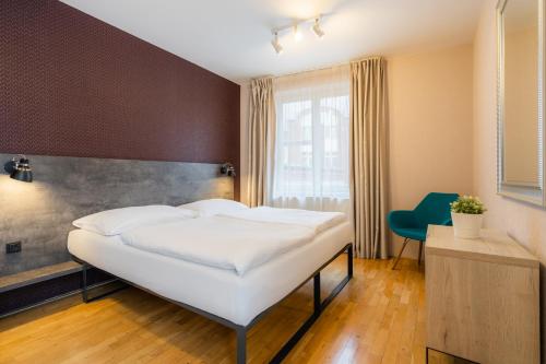 a bedroom with a white bed and a blue chair at EA ApartHotel Melantrich in Prague