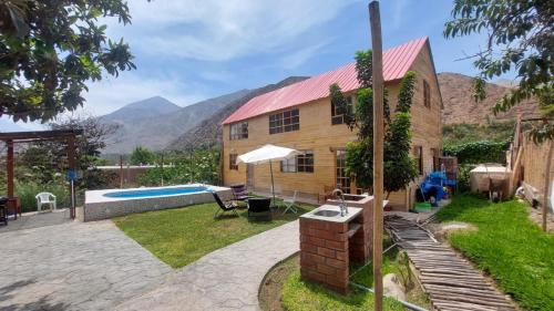 a wooden house with a swimming pool and mountains in the background at Casa de Campo Villa Angélica Lunahuaná in Lunahuaná