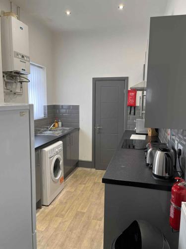 Complete 4 Bedroom House in Hanley-Free Parking في Hanley: مطبخ مع غسالة ملابس وغسالة