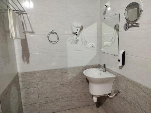 a white bathroom with a sink and a mirror at Nature's Deck - River Side Cabana's in Kārwār