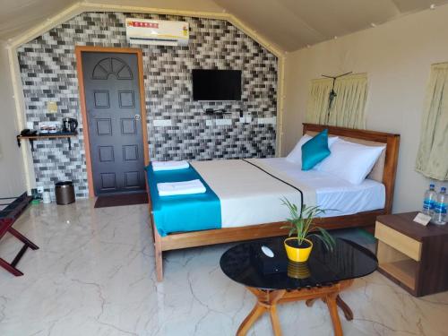 a bedroom with a bed and a tv on a wall at Nature's Deck - River Side Cabana's in Kārwār