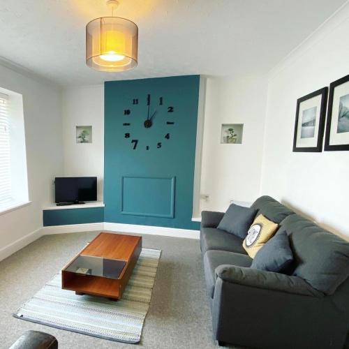 a living room with a couch and a clock on the wall at Liberty House in Weston-super-Mare