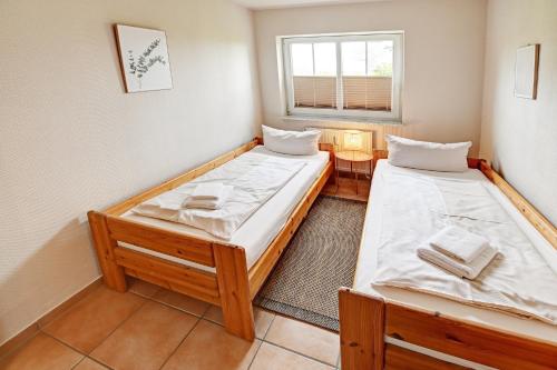 Duas camas num pequeno quarto com uma janela em fewo1846 - Am Strand - familienfreundliche Wohnung mit 2 Schlafzimmern, Terrasse und Garten em Harrislee