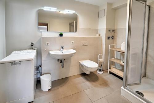 uma casa de banho com um lavatório, um WC e um espelho. em fewo1846 - Am Strand - familienfreundliche Wohnung mit 2 Schlafzimmern, Terrasse und Garten em Harrislee