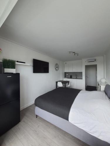 a bedroom with a large bed and a flat screen tv at Studio Julian in Middelkerke