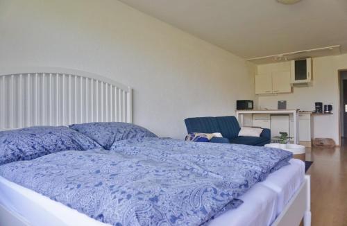 a bedroom with a bed with a blue comforter and a chair at Appartement Traumblick in Bad Reichenhall