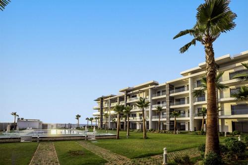 an apartment building with palm trees in the foreground at Appartement de luxe en bord de mer avec piscine in Mansouria