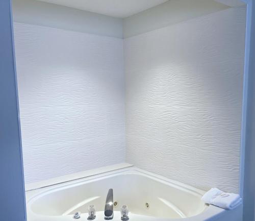 a white bathroom with a tub and a sink at Ramada by Wyndham Waupaca in Waupaca