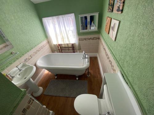 baño con paredes verdes, bañera y lavamanos en The Old Surgery Room Only, en Scarborough