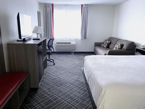 a hotel room with a bed and a tv and a couch at Ramada by Wyndham Waupaca in Waupaca