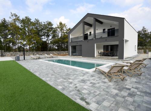 ein modernes Haus mit Pool und Rasen in der Unterkunft VIlla Luka - new isolated villa with heated pool, jacuzi and sauna in Gračac