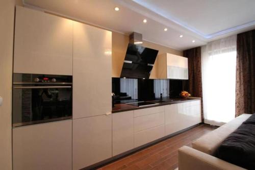 a kitchen with white cabinets and a couch at Central Apartments Sz7-66 in Gdańsk