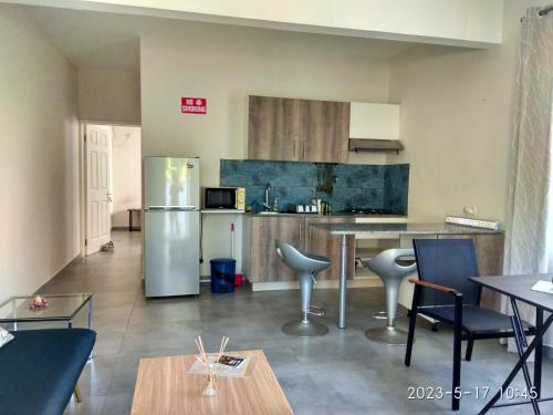 a kitchen with a refrigerator and a table and chairs at APPARTMENT( LA PAPAYA) in La Gaulette