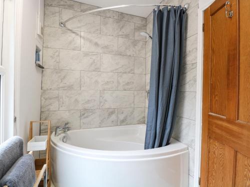 a bathroom with a tub and a shower curtain at Unthank Cottage in Norwich