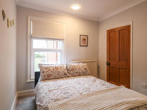 a bedroom with a bed and a window at Unthank Cottage in Norwich