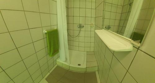 uma casa de banho em azulejos brancos com um lavatório e um chuveiro em Kamp restavracija Gladiator em Žetale
