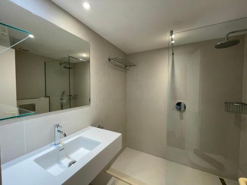 uma casa de banho com um lavatório, um chuveiro e um espelho. em ES CASTELL 1 6 by SOM Menorca em Fornells