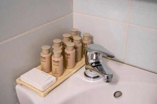a bathroom sink with four bottles of soap on it at Cozy apartment in the best part of Pagkrati in Athens