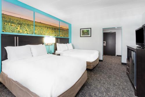 a hotel room with two beds and a flat screen tv at Days Inn by Wyndham Livonia Canton Detroit in Livonia