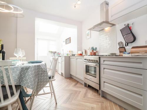 a kitchen with white cabinets and a table with a table cloth at Sea Mouse Cottage in Southwold