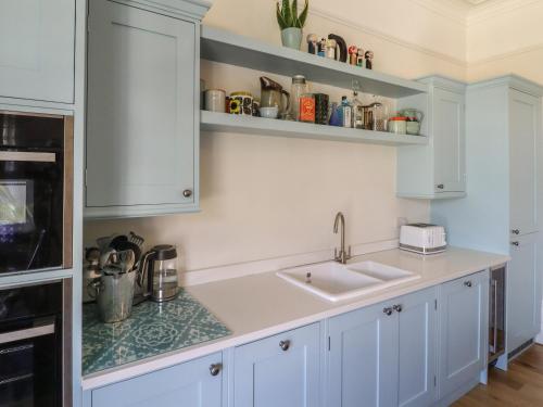 a kitchen with white cabinets and a sink at Archery Retreat in St. Leonards