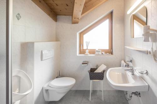 a white bathroom with a toilet and a sink at Residence Lärchwiese in San Giacomo
